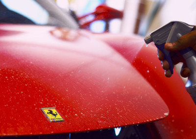 Slip solution being sprayed on a red Ferrari hood during a PPF install