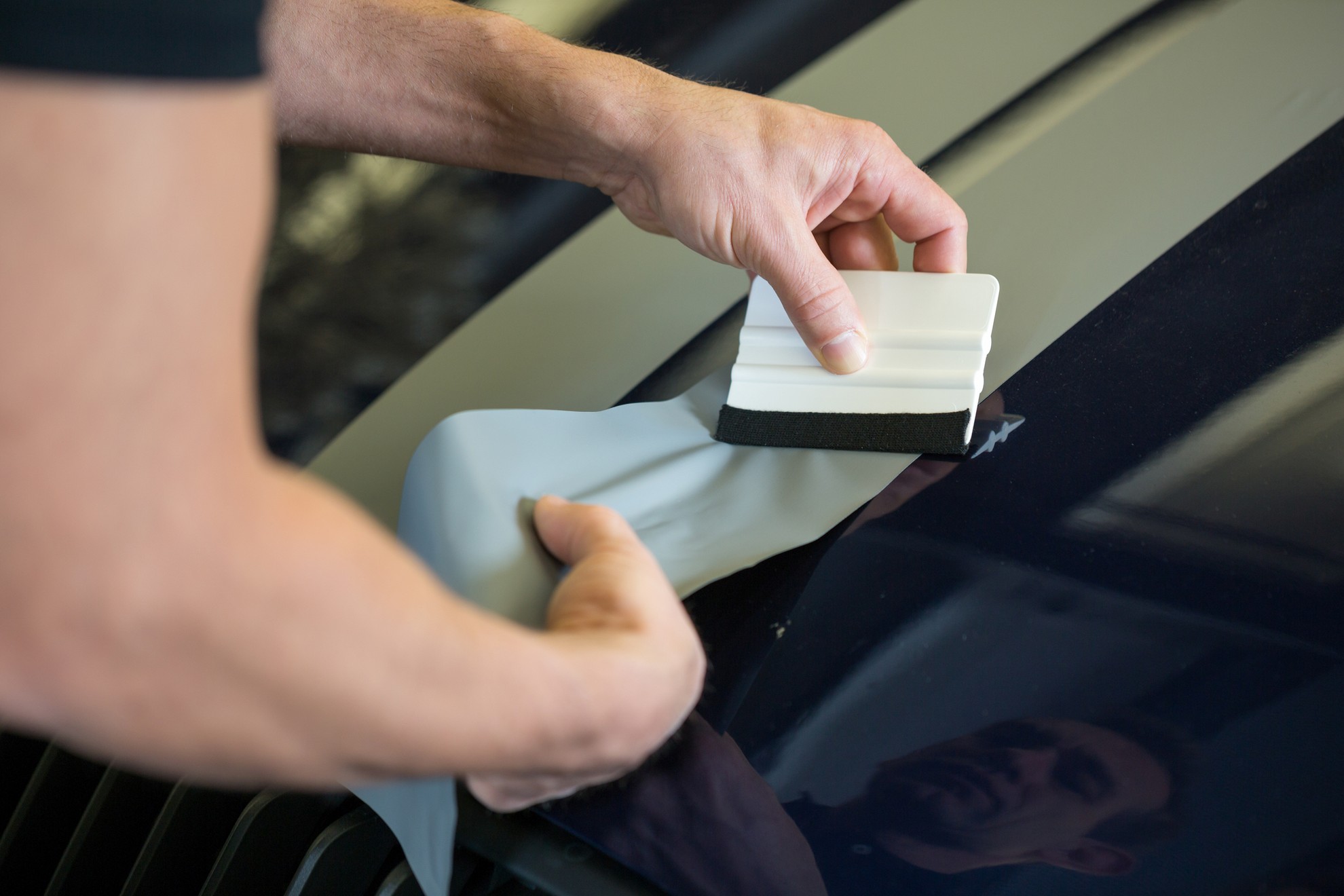 Close-up of window film being squeegeed onto a car window