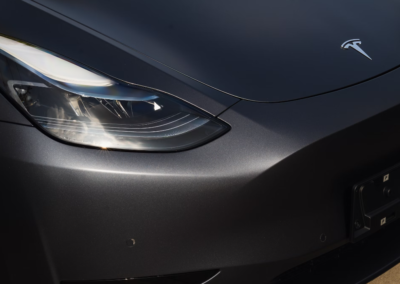 Front detail of a matte black wrapped Tesla showing a timeless black finish