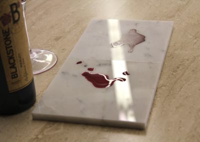 Red wine pooled on a marble countertop sample protected by Stone Guard film