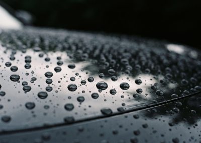 Water beading tightly on the dark ceramic coated hood of a car detailed by Monumental Workx in San Diego